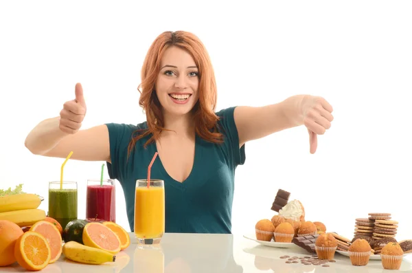 Женщина, выбирая между фрукты, пюре и органических здоровое питание против сладости, сахар, много конфет, нездоровой пищи — стоковое фото